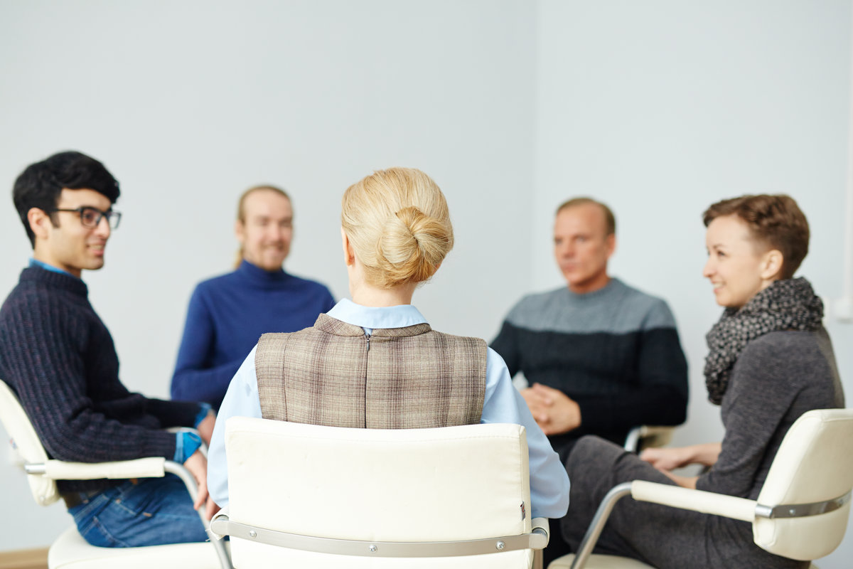 Rear view of counselor consulting young people