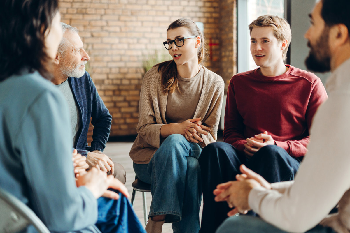 Psychotherapist leading group therapy session with patients sitting in circle, sharing experiences and supporting each other, fostering mental well-being and recovery. Psychology concept