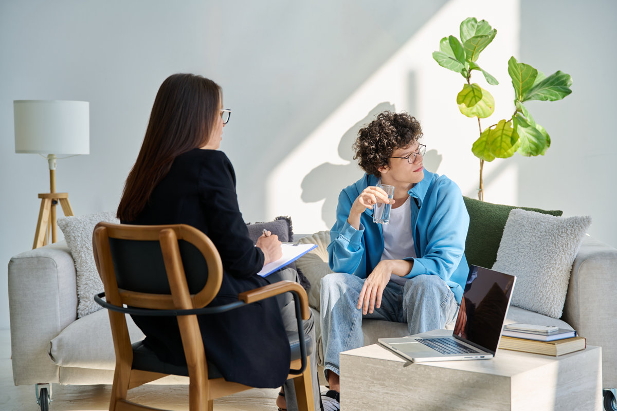 Young man in mental session talking with professional psychologist. Female psychiatrist counselor social worker working with patient. Psychology psychiatry therapy treatment support help youth